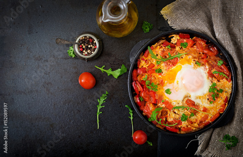 Breakfast. Fried eggs with vegetables - shakshuka in a frying pan on a black background in the Turkish style. Flat lay. Top view