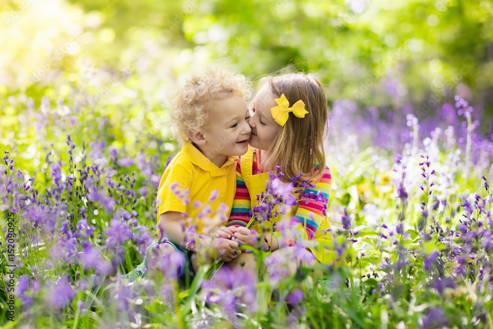 Kids playing in blooming garden with bluebell flowers Kids playing in blooming garden with bluebell flowers