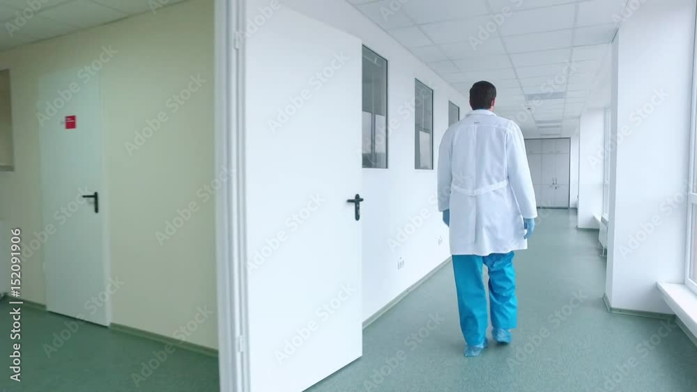 Scientist walking lab corridor. Back view of doctor walking hospital corridor in white coat. Male scientist in uniform going laboratory corridor. Medical worker go lab corridor Scientist walking lab corridor. Back view of doctor walking hospital corridor in white coat. Male scientist in uniform going laboratory corridor. Medical worker go lab corridor