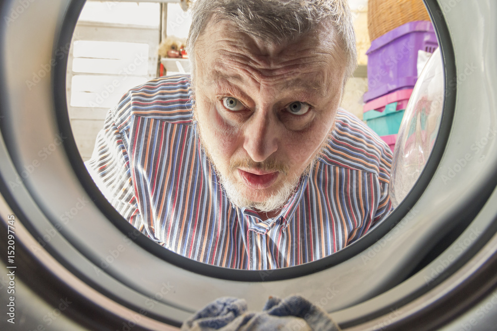 Mann schaut in die Waschmaschine