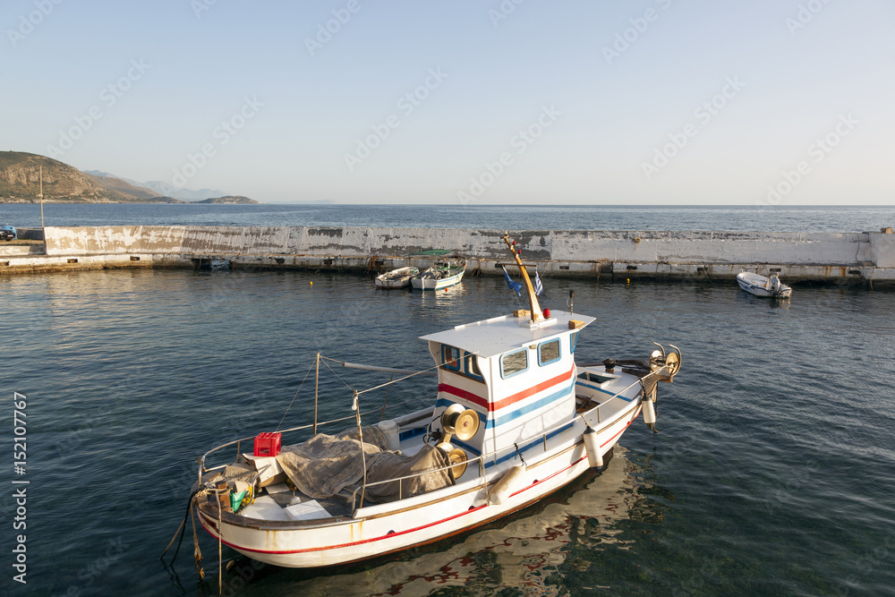 small fishing boat in harbor of agios nicolaos on greek peloponnese with sea and mountains in the background