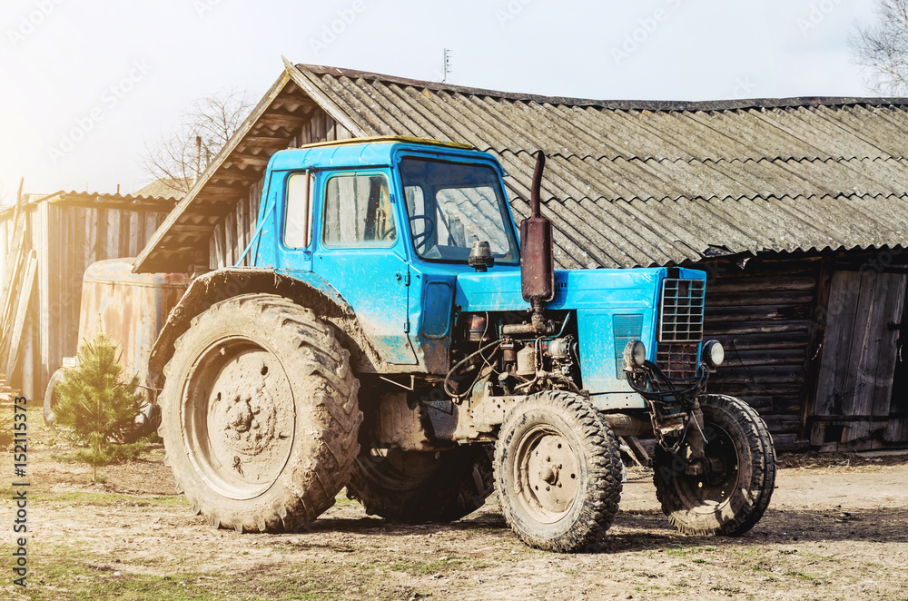 Obraz premium An old tractor in the countryside amid barns and sheds.