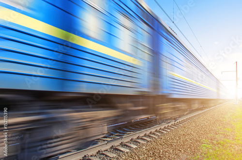 Passenger blue wagons at a speed passing railway.