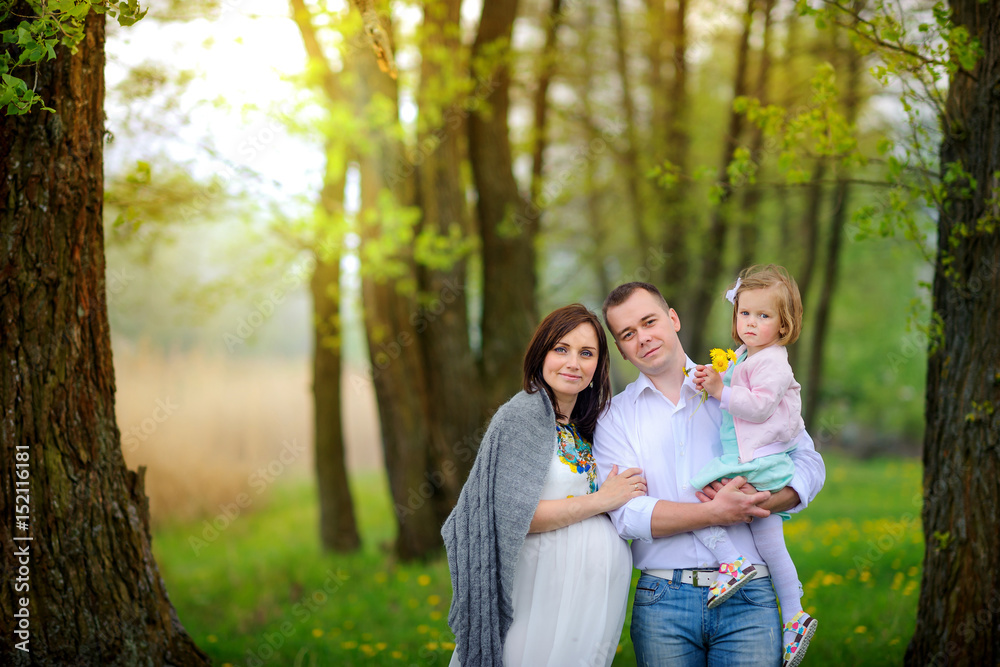 happy family walks in the park on a sunset, father keeps little subsidiary on hands, embrace and smile happy family walks in the park on a sunset, father keeps little subsidiary on hands, embrace and smile