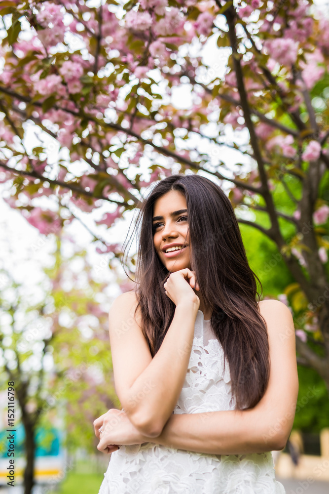 Portrait of beautiful young woman enjoying sunny day in park during cherry blossom season on a nice spring day Portrait of beautiful young woman enjoying sunny day in park during cherry blossom season on a nice spring day