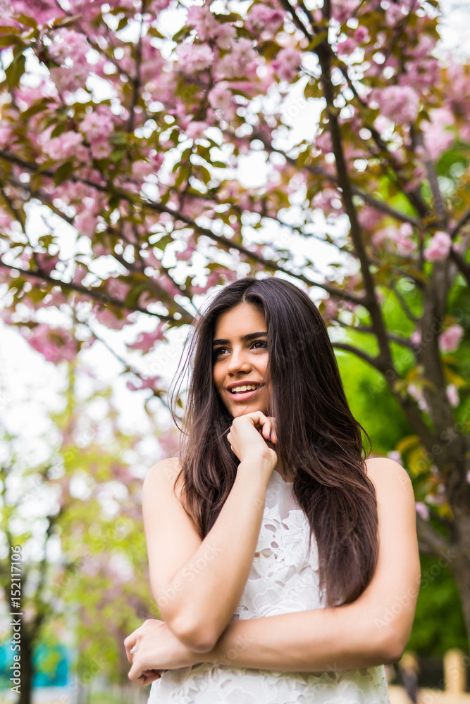 Portrait of beautiful young woman enjoying sunny day in park during cherry blossom season on a nice spring day Portrait of beautiful young woman enjoying sunny day in park during cherry blossom season on a nice spring day