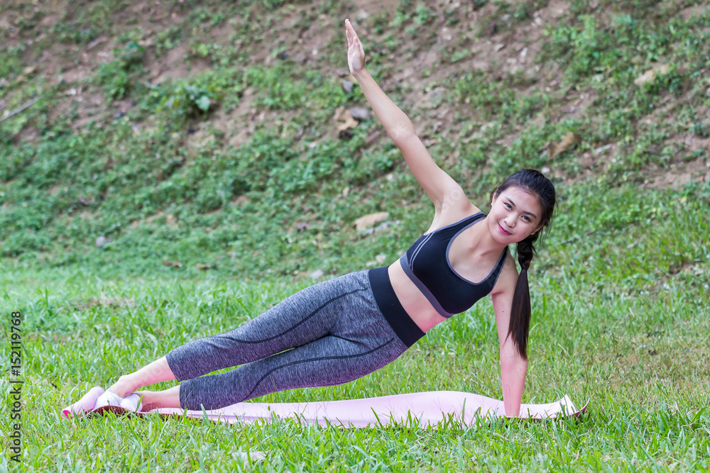 Fototapeta premium Pretty asian girl practicing the side plank yoga pose on yoga mat