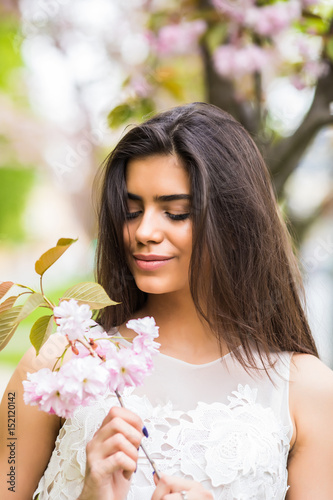 Joyful positive caucasian woman posing with flowering sakura tree. photo