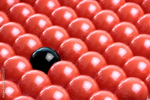 Different black ball in red balls. Conceptual image.
