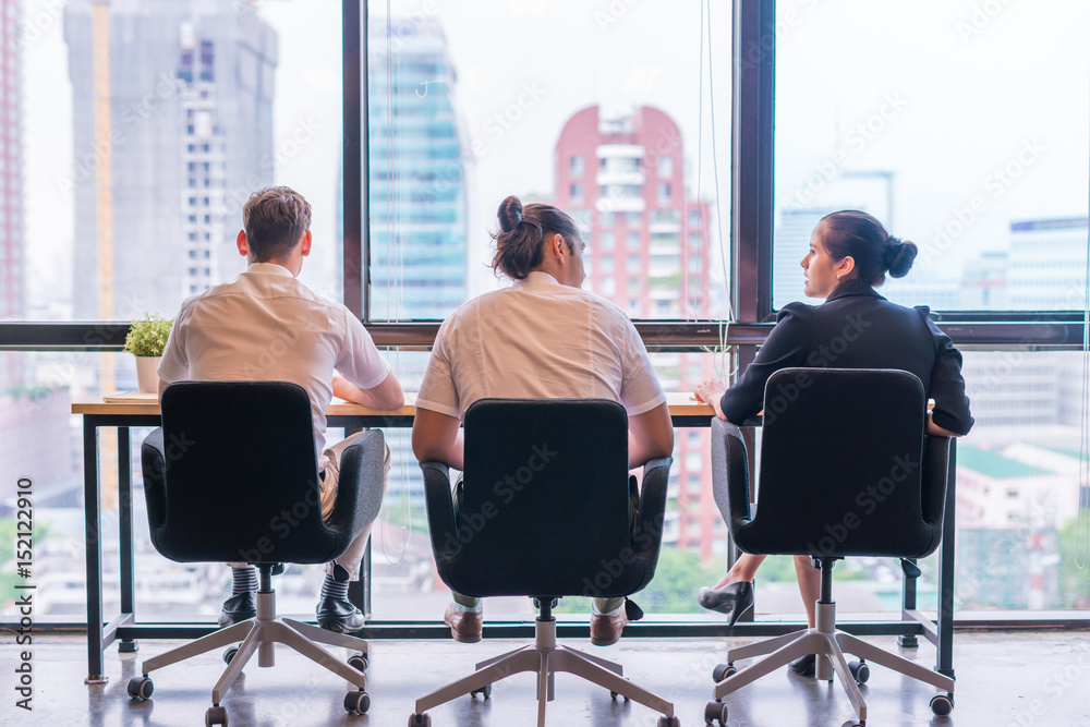 Tree young Caucasian office businessman and business woman meeting, discussing business, sitting at the table, city view Tree young Caucasian office businessman and business woman meeting, discussing business, sitting at the table, city view