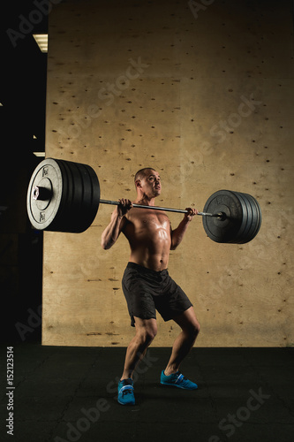 Handsome man with big muscles, posing in the gym muscular man lifting weights over dark background muscular man working out in gym doing exercises with barbell at biceps strong male