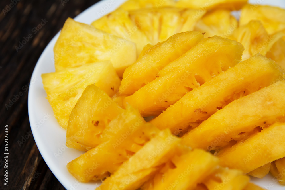Sliced pineapple on the white plate on wooden table Sliced pineapple on the white plate on wooden table