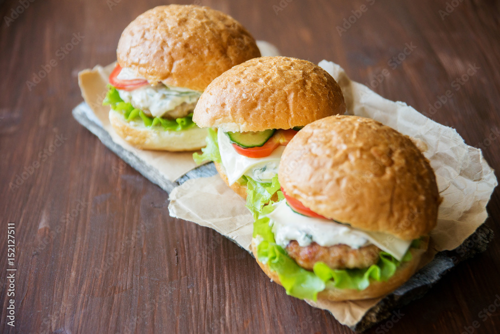 Closeup of home made burgers on wooden background Closeup of home made burgers on wooden background