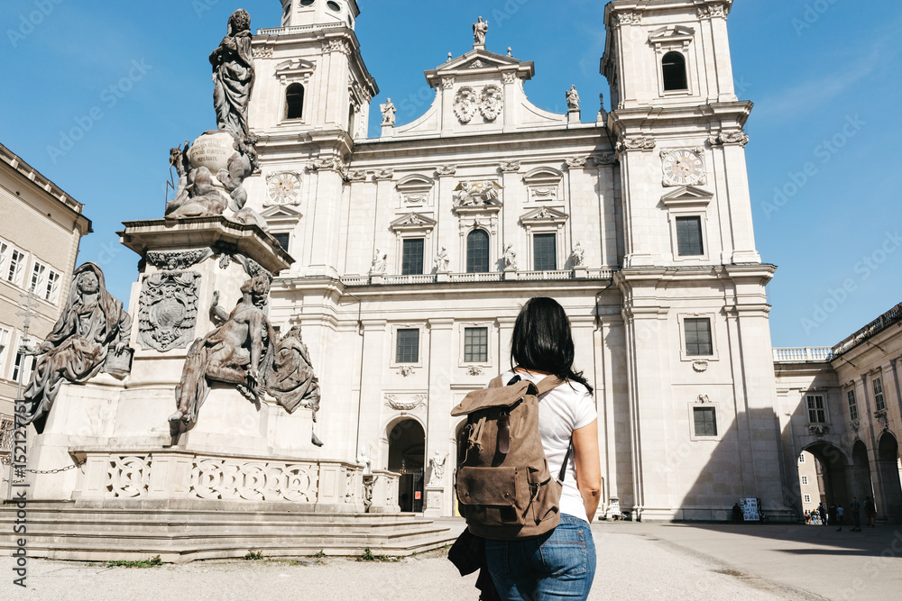 Girl traveler with a backpack near the famous cathedral Salzburg (Salzburger Dom) at Domplatz, Salzburg Land, Austria