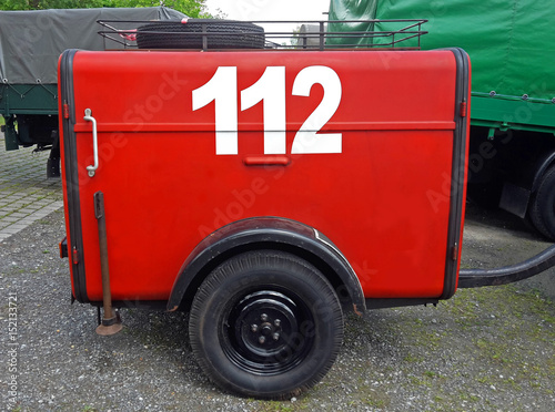 old red German fire department trailer with the fire emergency phone number painted on it