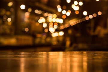 Wood table top with reflect on blur of lighting in cafe,restaurant background/selective focus.