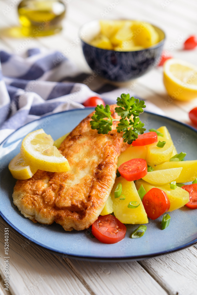 Fried fish fillets in batter, served with potato, tomato and scallion