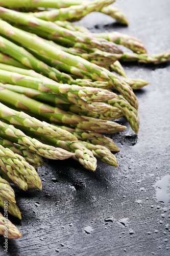 Green asparagus with water drops on black wooden table