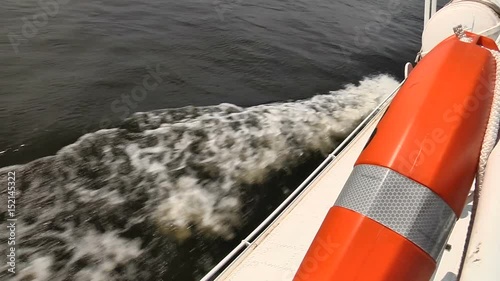 Wave from a floating vessel with a life raft in the foreground photo
