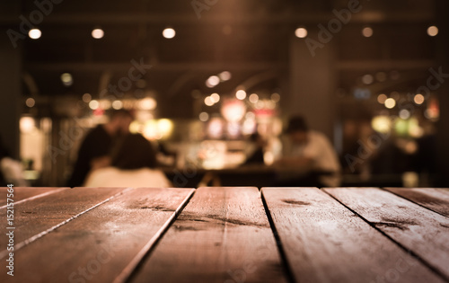 Wood table top with blur light bokeh in dark night cafe,restaurant background .Lifestyle and celebration concept