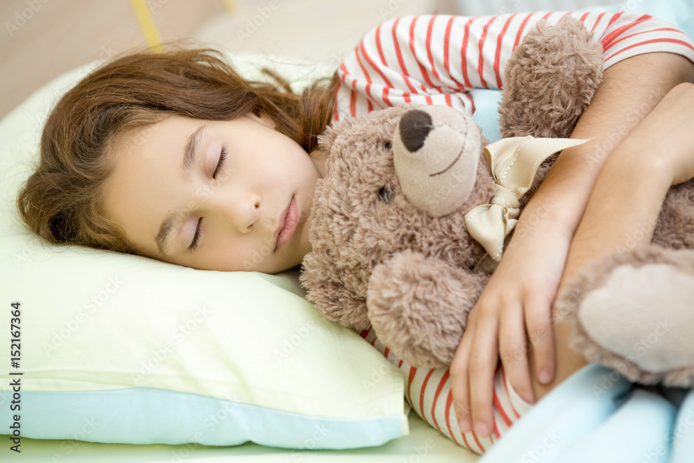 Pretty young girl sleeping in her bed with a teddy bear Pretty young girl sleeping in her bed with a teddy bear