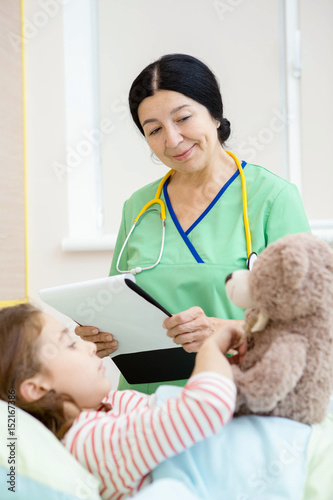 Cheerful young girl and her pediatrician at the hospital ward