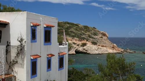 Traditional ibicencan house with the ocean and an island with a cave in the background photo