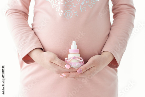 Belly of a pregnant woman Hands hold Bottle of milk photo