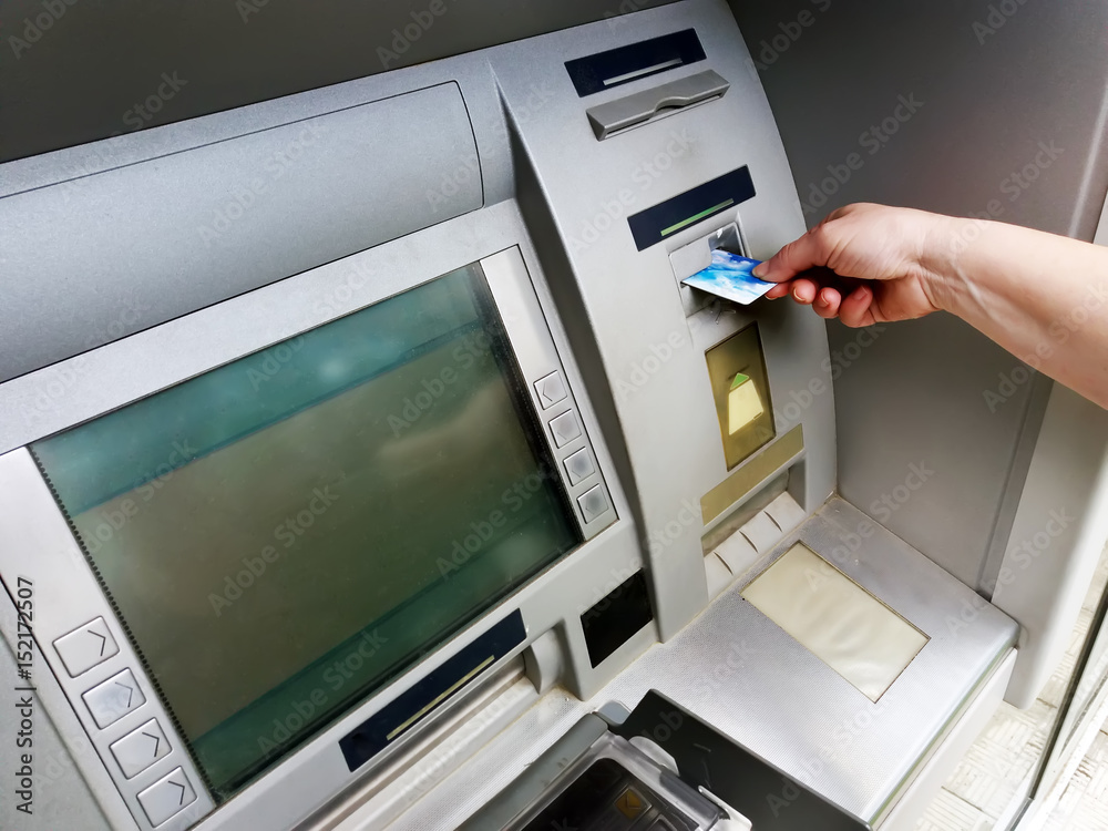 Hand inserting ATM card into bank machine to withdraw money Hand inserting ATM card into bank machine to withdraw money