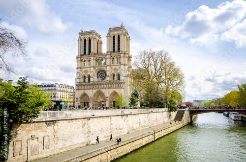 Notre Dame de Paris Cathedral on de Ile de la Cite in the beautiful European city with the Seine river flowing on the right and many tourists visiting the monument © alexionas