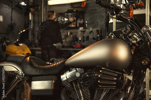 Bearded young man repairing his motorbike at the workshop