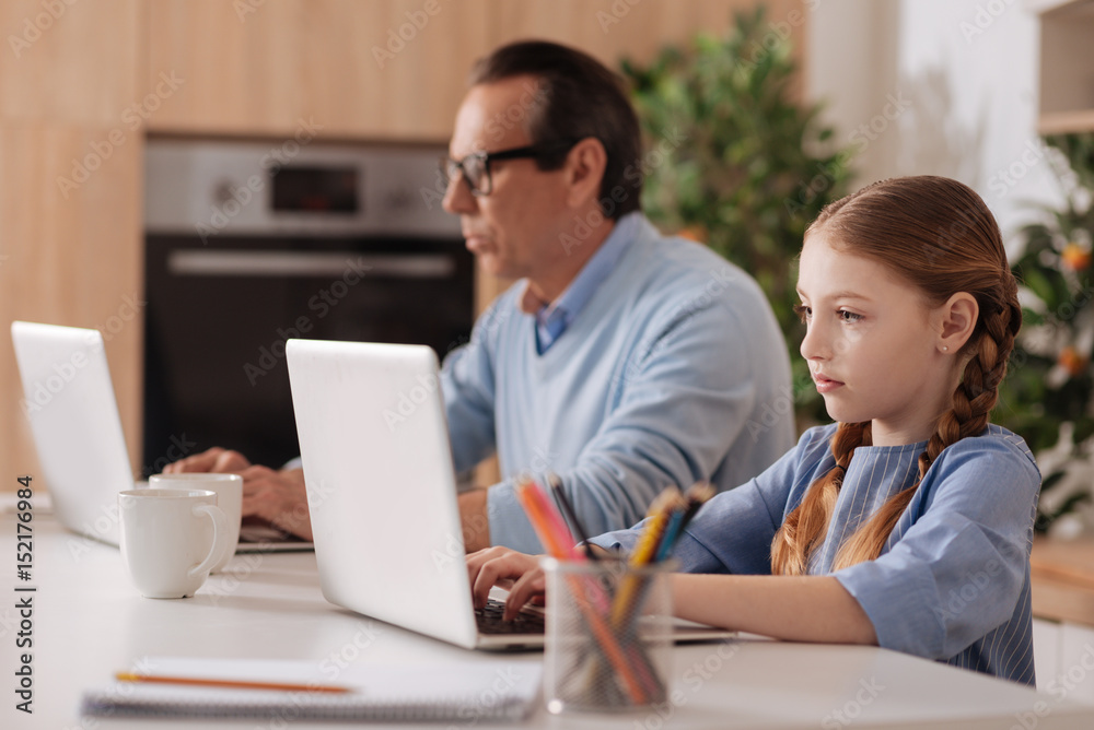 Internet addicted grandfather and granddaughter using laptops indoors Internet addicted grandfather and granddaughter using laptops indoors