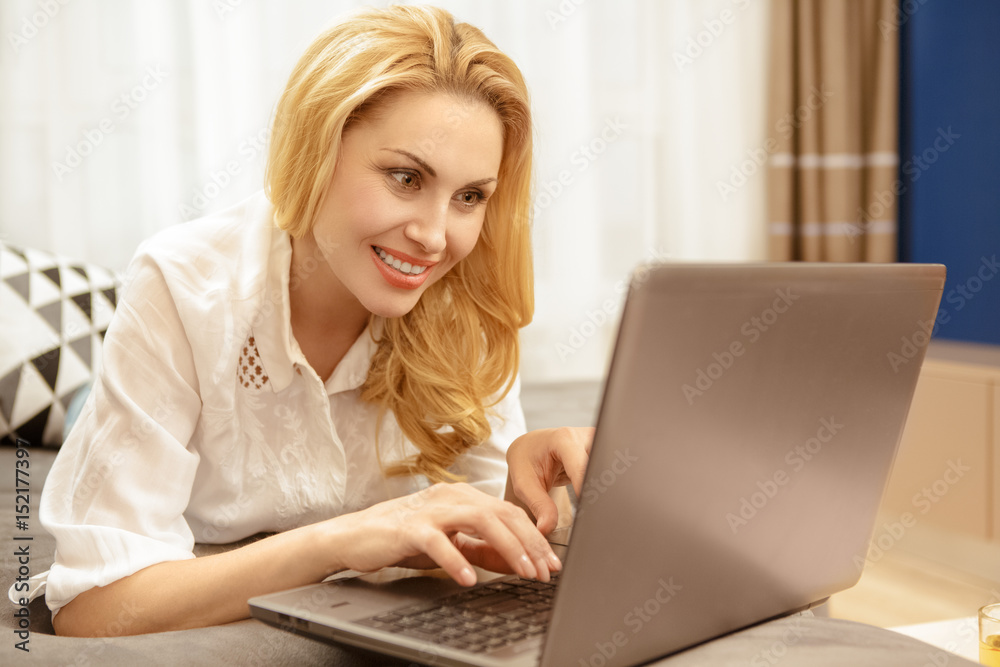 Gorgeous mature woman using a laptop resting at her house