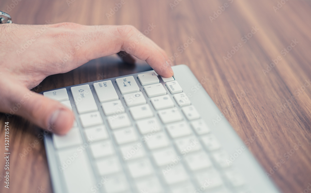 Man's hand pressing escape button on wireless keyboard on wooden table. Key combination. Man's hand pressing escape button on wireless keyboard on wooden table. Key combination.