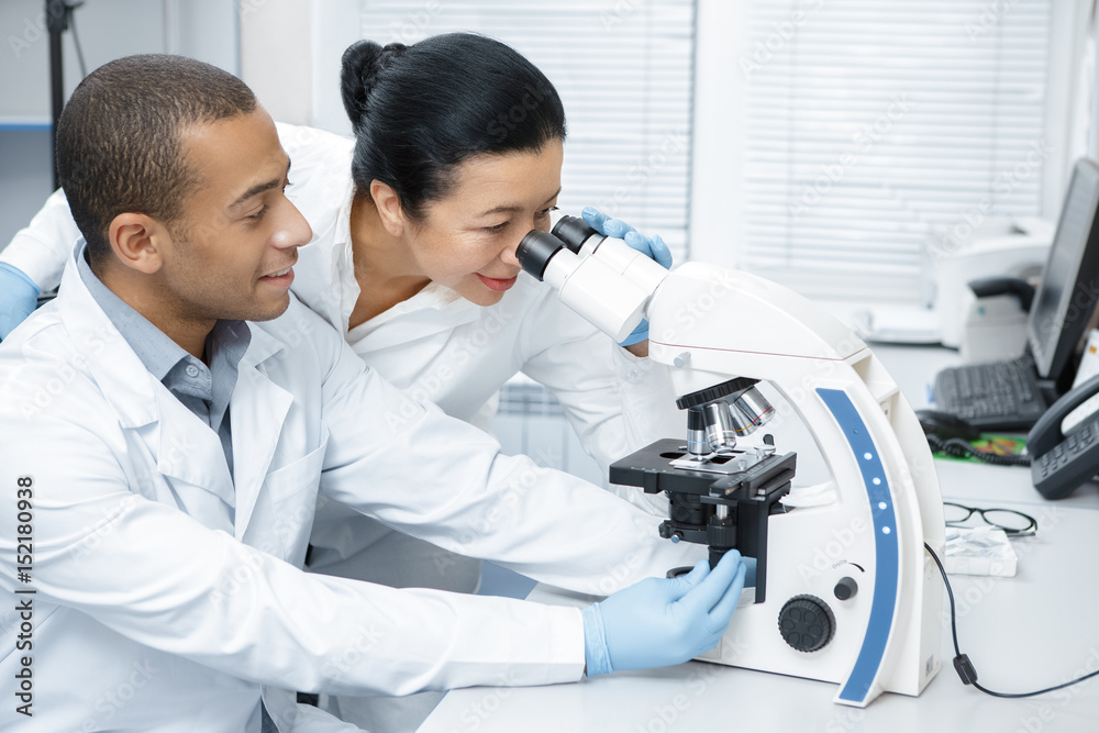 Two colleagues professional researchers using microscope at the laboratory Two colleagues professional researchers using microscope at the laboratory