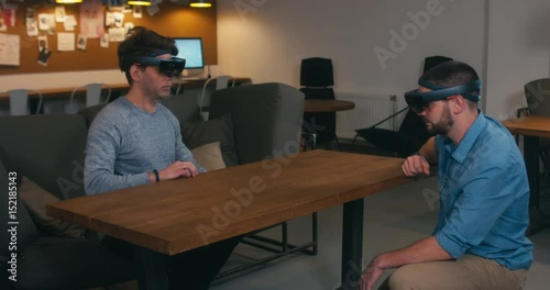 Young adult Caucasian male colleagues using holographic augmented reality glasses together. 4K UHD RAW edited footage photo