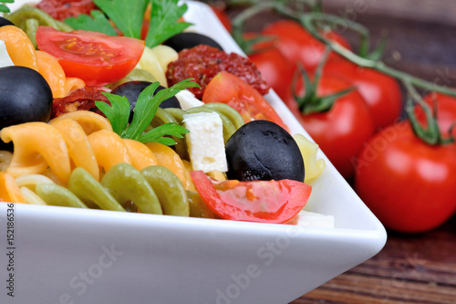 Fusilli with tomato, cheese and olive in a bowl