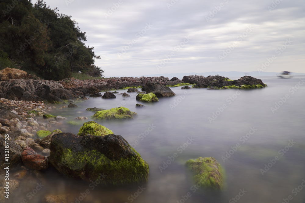 Obraz premium Long Exposured Rocky Beach with Green Seaweeds On The Rocks 