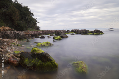 Long Exposured Rocky Beach with Green Seaweeds On The Rocks 