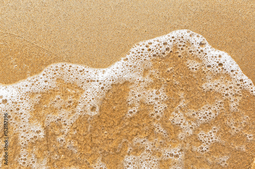 Wave of the sea on yellow sandy beach. Summer vacation background. Wet sand texture. photo
