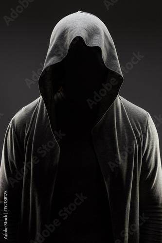 Fotografia mysterious man in the hood with hidden face over dark grey background