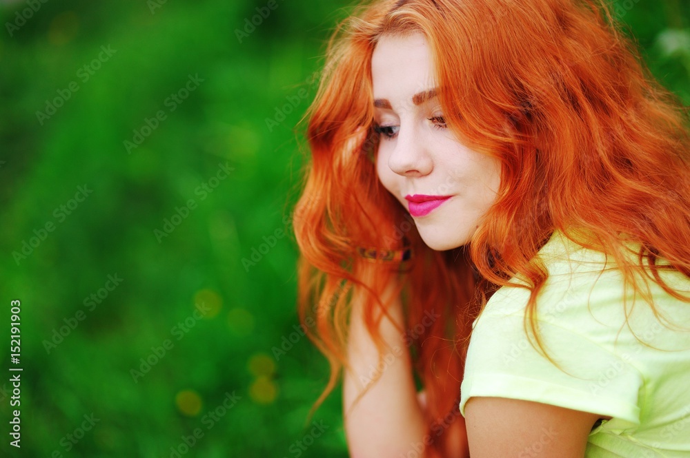 Gorgeous portrait of adorable redhead Caucasian girl with lowered eyes on blurred green background, closeup