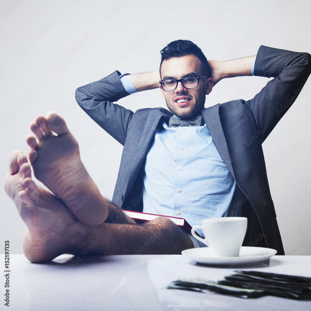 Businessman sitting in office with feet up on desk - Stock Photo