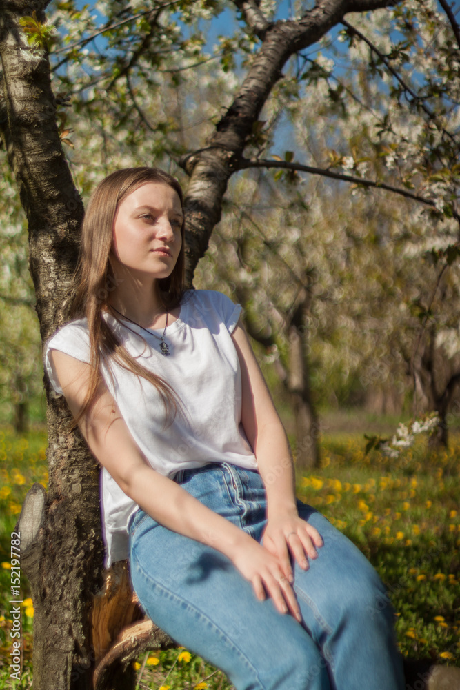 Portrait of beautiful young woman in apple trees blooming park on a sunny day. Smiling girl Happy girl. Happiness concept.