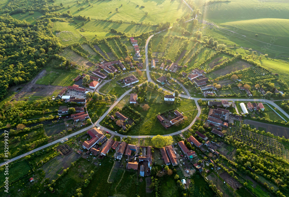 Beautiful unique circular village in Romania seen from above at the sunset by a professional drone with soft nice lens flare  - obrazy, fototapety, plakaty 