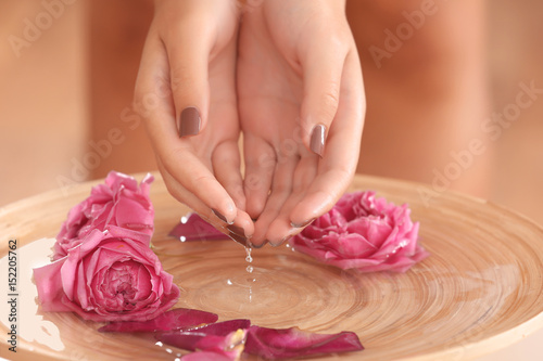 Female hands in spa wooden bowl with flowers, closeup