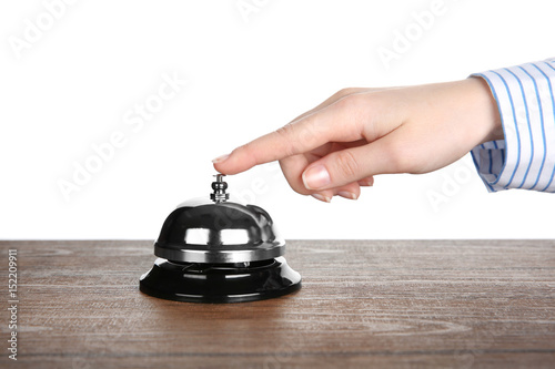 Female hand ringing a service bell on wooden table against white background