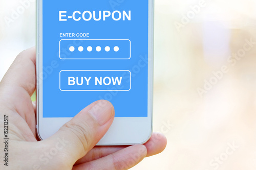 Hand holding smart phone with discount coupon code on screen over blur store background, on line shopping ,business, E-commerce, technology and digital marketing background