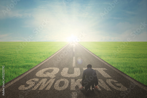 Male manager kneeling on the quit smoking text