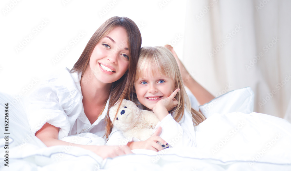 Woman and young girl lying in bed smiling